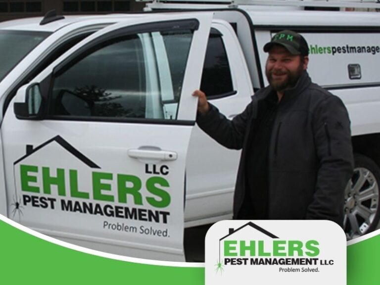 A local pest control technician stands in front of his work truck.