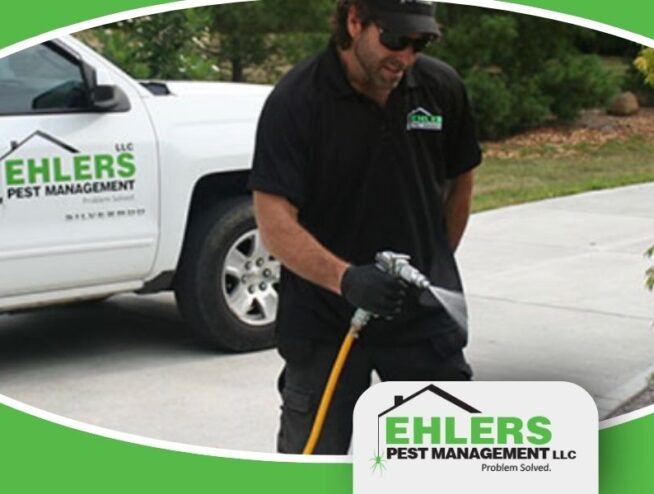 A local pest control technician stands in front of his truck