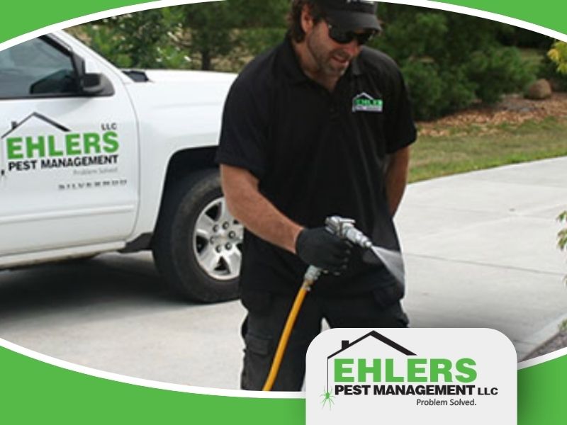 A local pest control technician stands in front of his truck